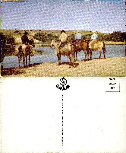 Cowboys on horseback by a lake